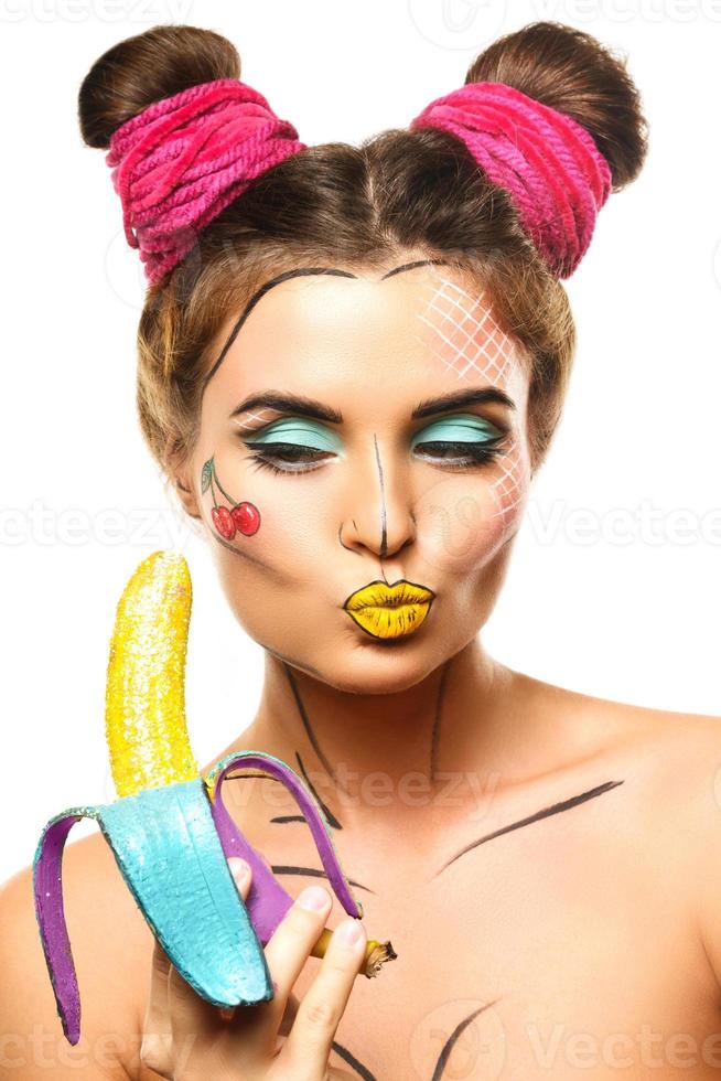 Beautiful model with creative pop art makeup holding banana photo