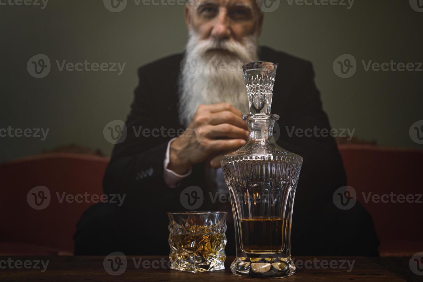 Handsome and bearded senior man drinking whiskey photo