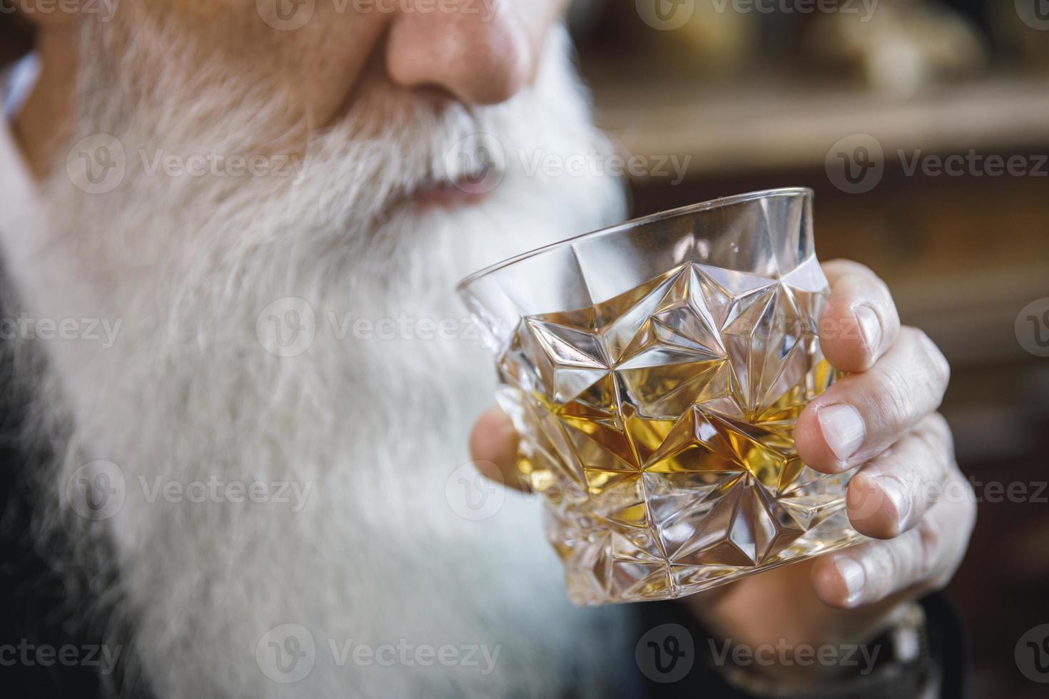 apuesto anciano barbudo con un vaso de whisky foto