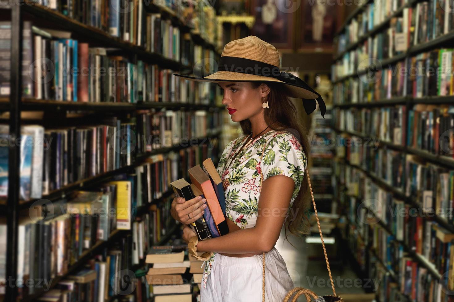 Beautiful girl wearing stylish outfit looking for interesting book in the vintage bookstore photo
