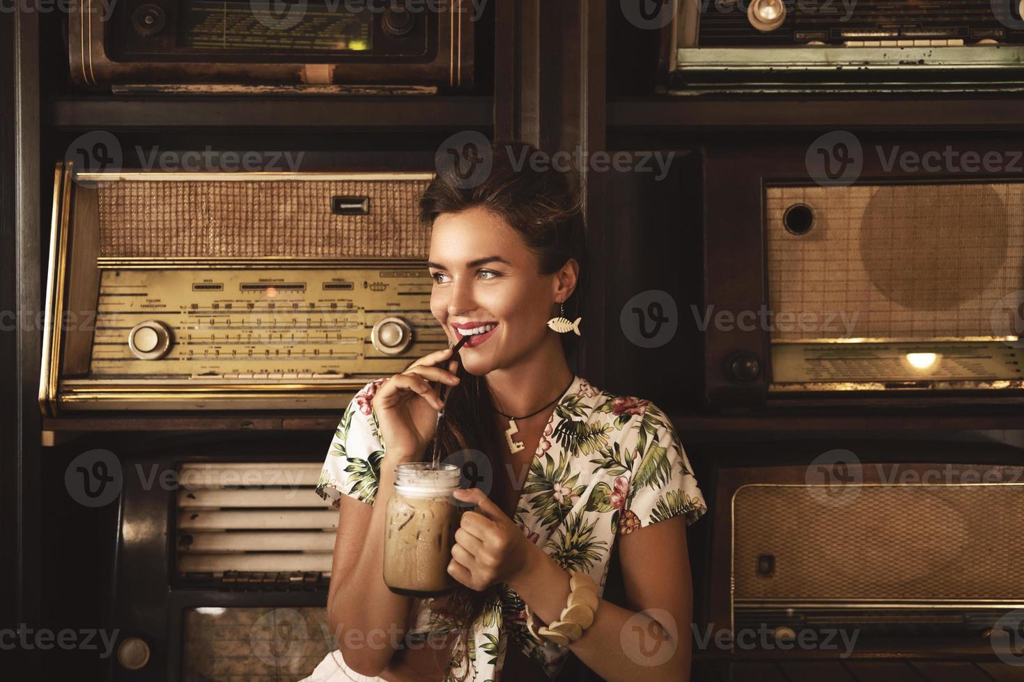 joven mujer feliz bebiendo café helado en un elegante café retro foto