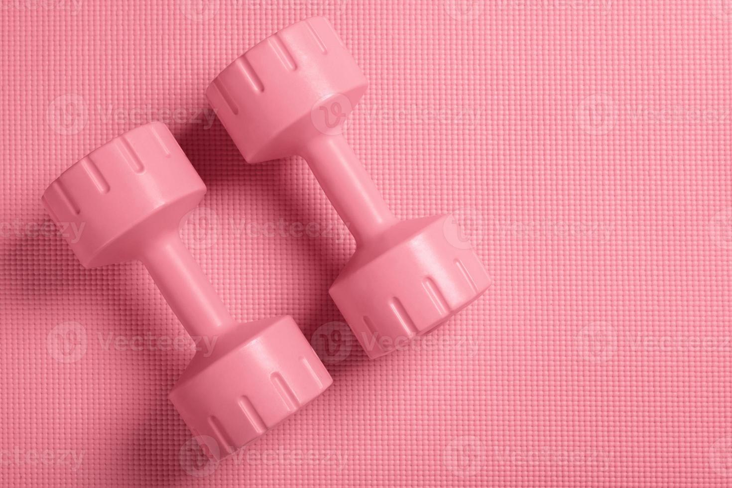 Pink dumbbells on the pink fitness mat photo