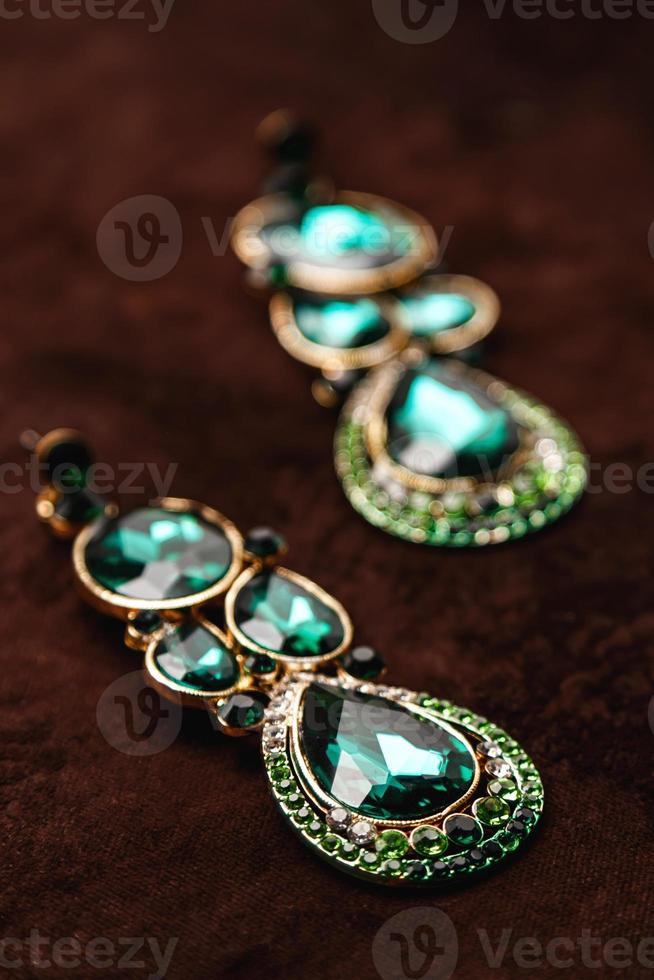 Luxury earrings with green gemstones on the brown velvet photo