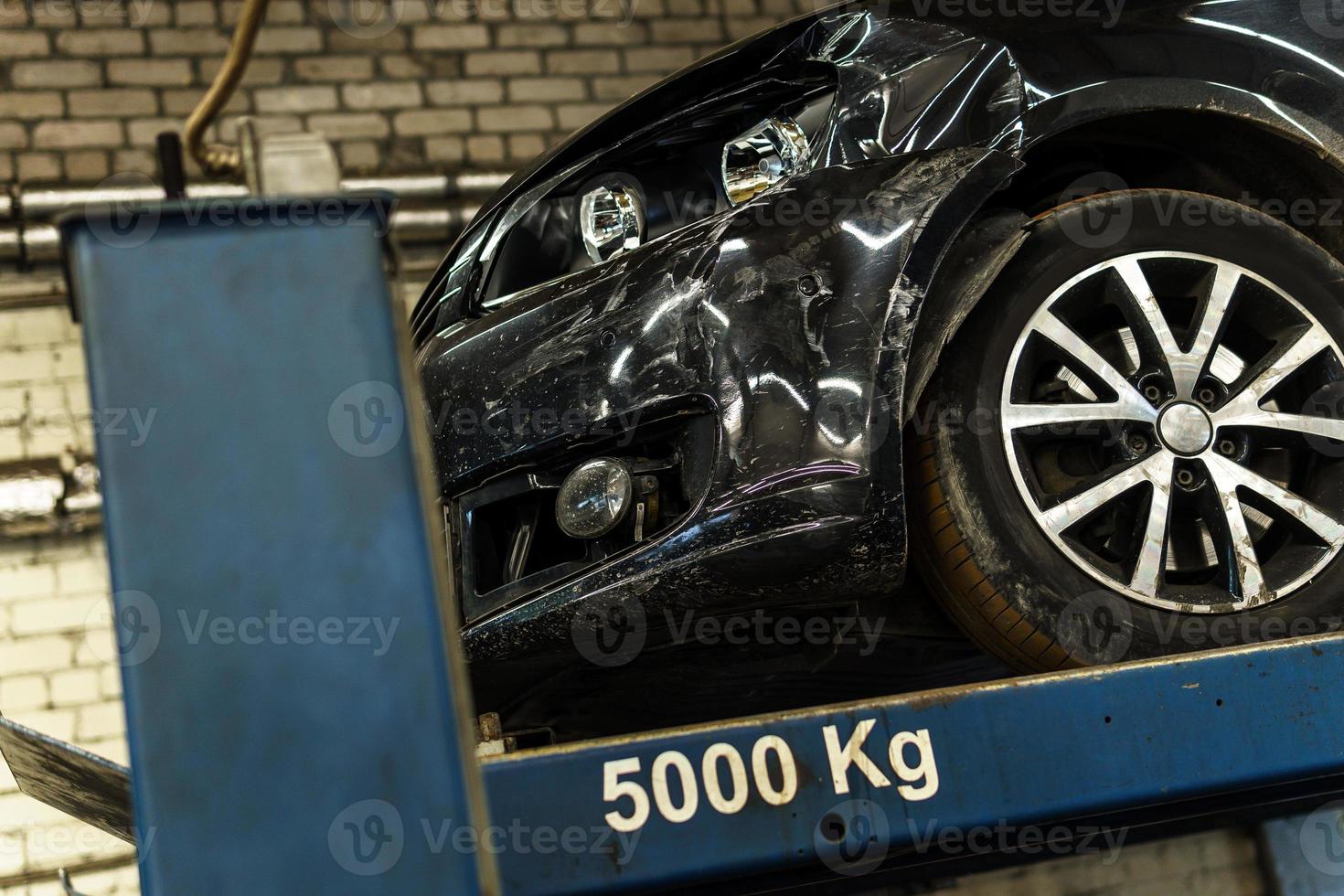 Broken car on the vehicle lifter in the repair shop photo