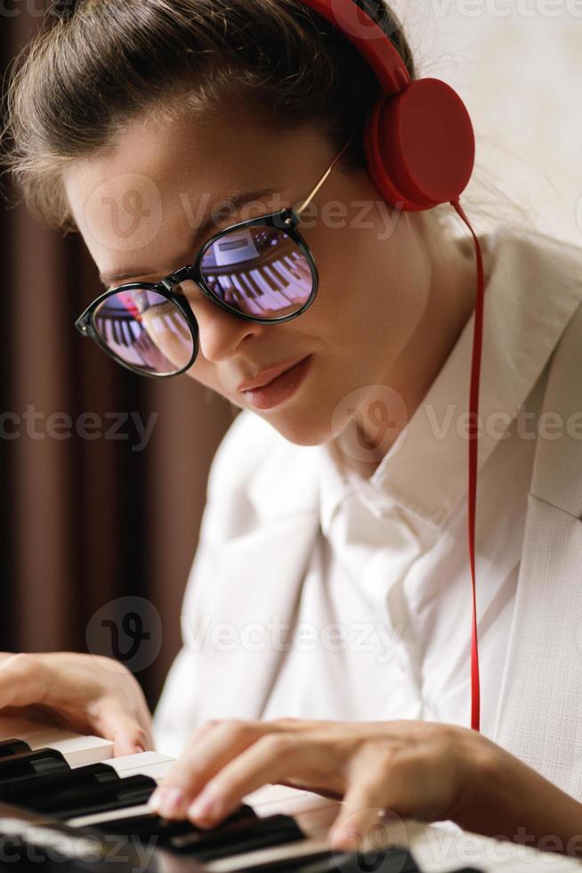 Young woman composer with a reflection of piano keys in a eyeglasses photo