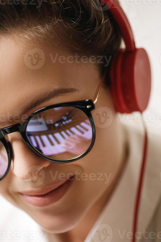 Young woman composer with a reflection of piano keys in a eyeglasses photo