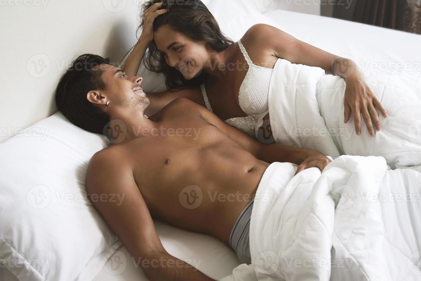 una pareja joven y hermosa está acostada en la cama por la mañana foto