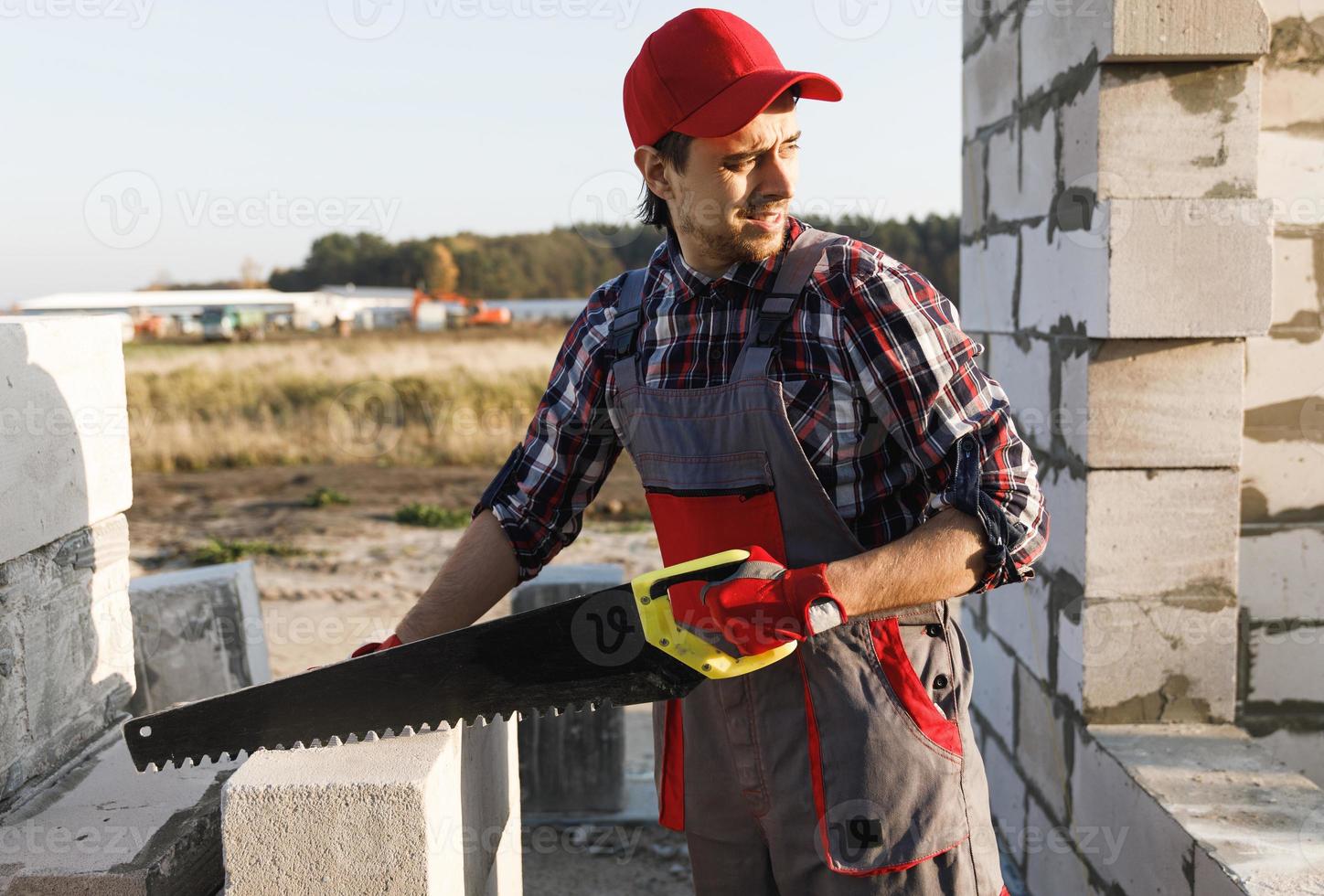 Bricklayer man is sawing autoclaved concrete blocks photo