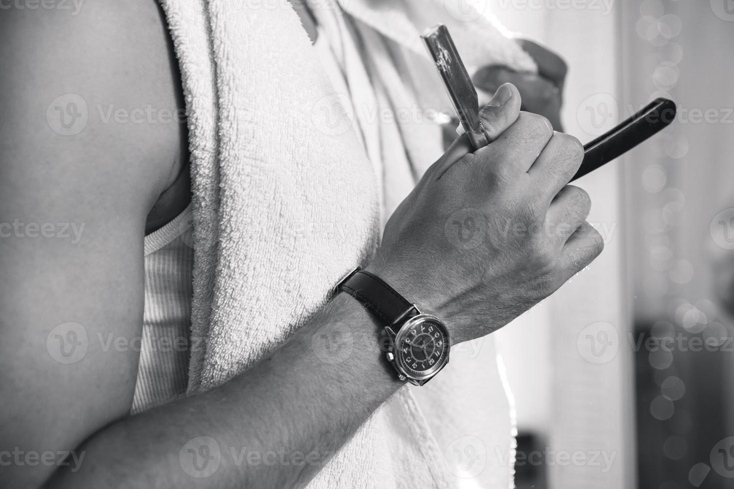 hombre afeitándose la barba con una navaja de afeitar foto