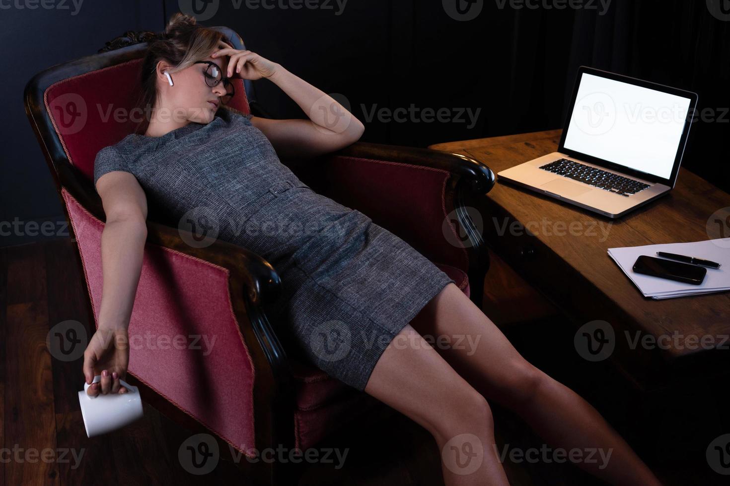 Tired and sleepy businesswoman is lying in the chair after long working day photo