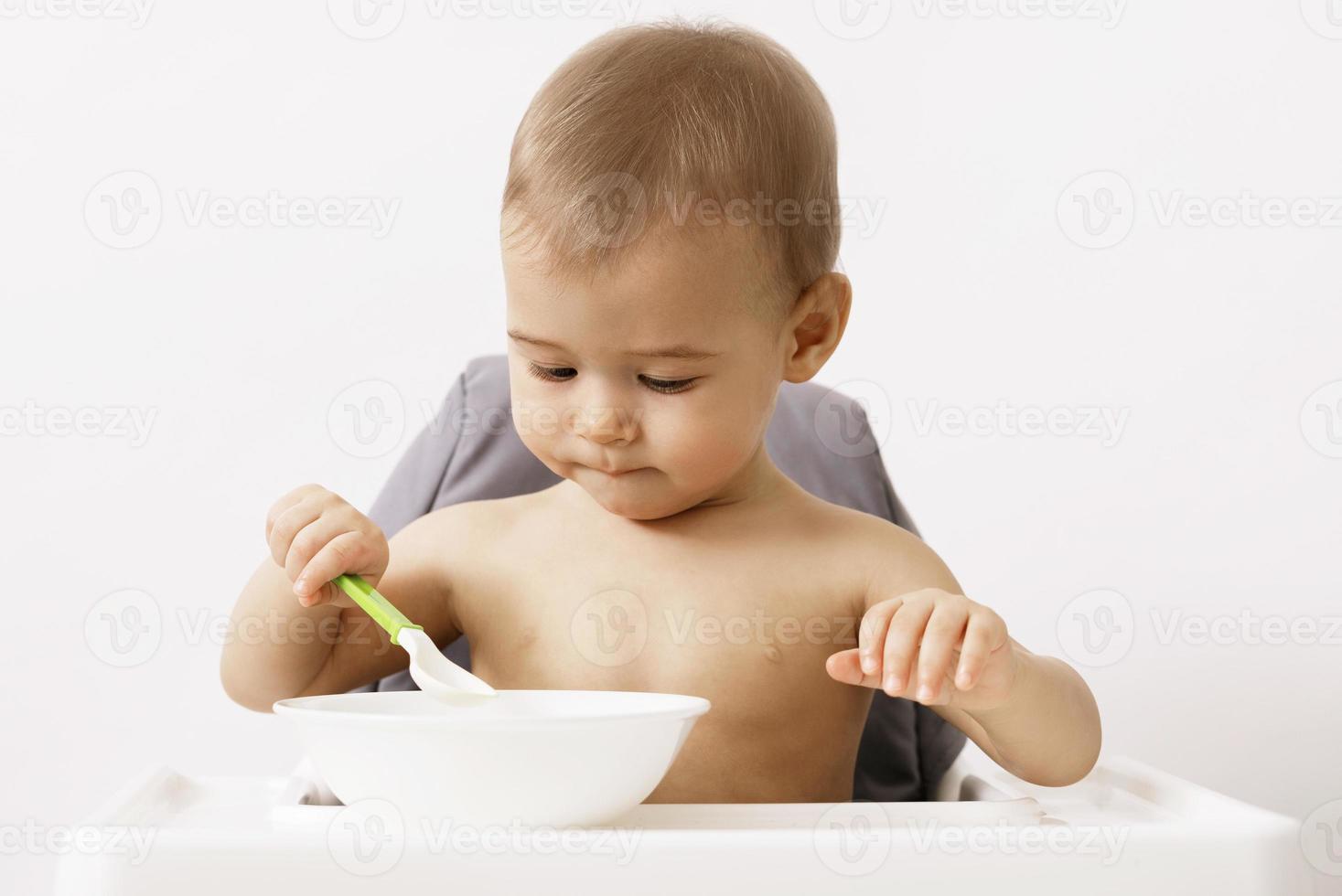 Cute hungry baby sitting in the high chair photo