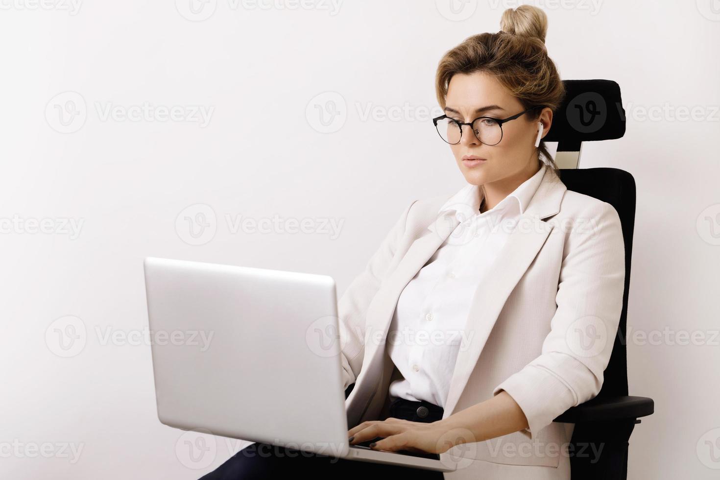 Businesswoman sitting on the office chair and using laptop pc photo