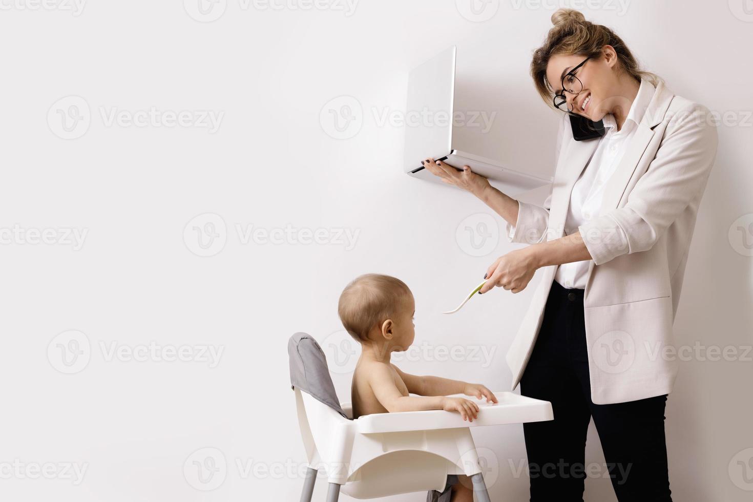 Young and busy businesswoman is working and holding her little baby photo