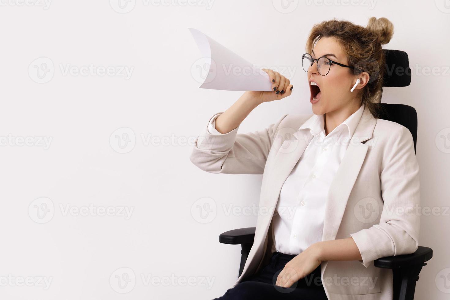mujer de negocios motivada gritando en la hoja de papel enrollada como un altavoz foto