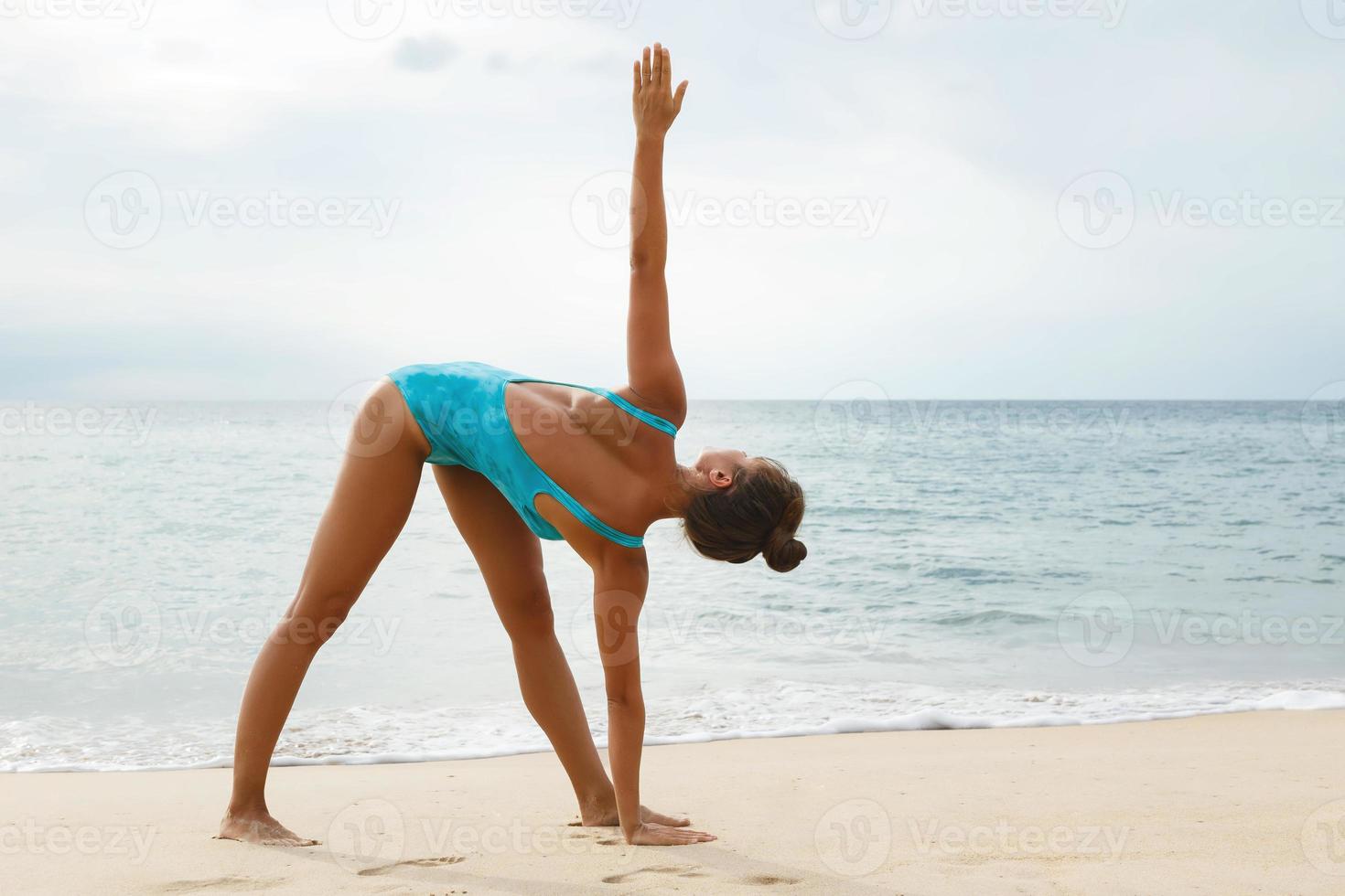 Woman doing yoga exercises on the beach photo