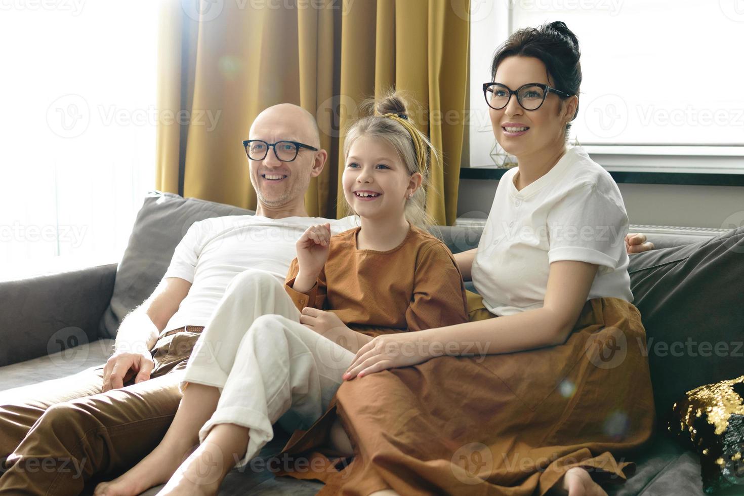 familia feliz viendo el programa de televisión juntos sentados en el sofá foto