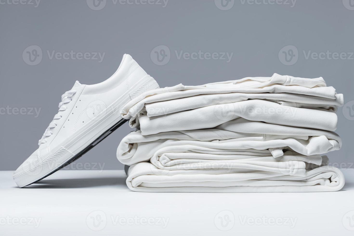 Stack of white clothes and stylish trainers photo