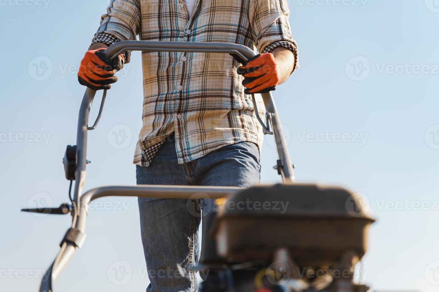 Man using aerator machine to scarification and aeration of lawn or meadow photo