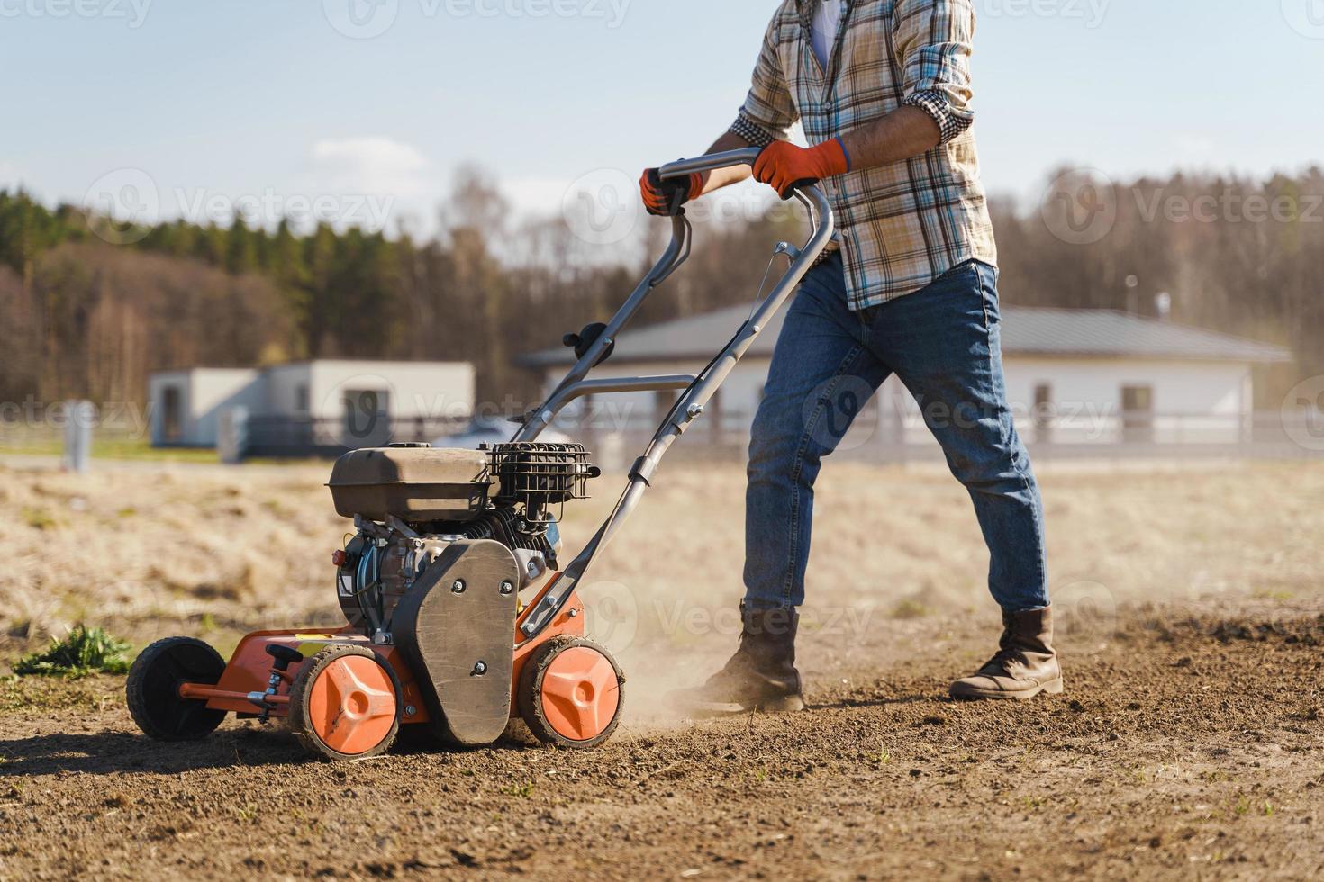 Man using aerator machine to scarification and aeration of lawn or meadow photo