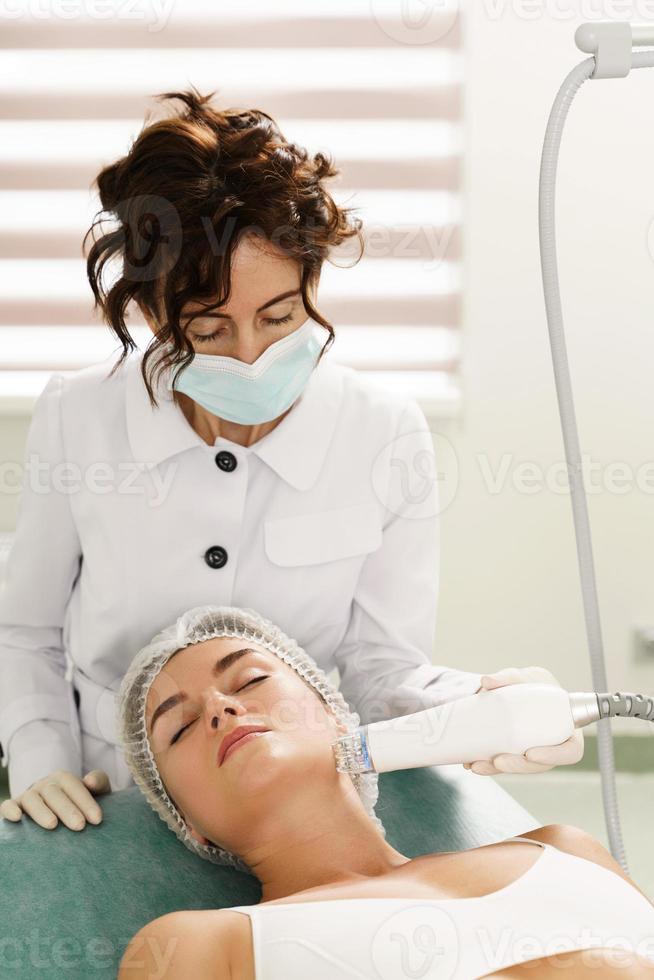 Doctor and woman client during radiofrequency lifting treatment in a medical aesthetic clinic photo