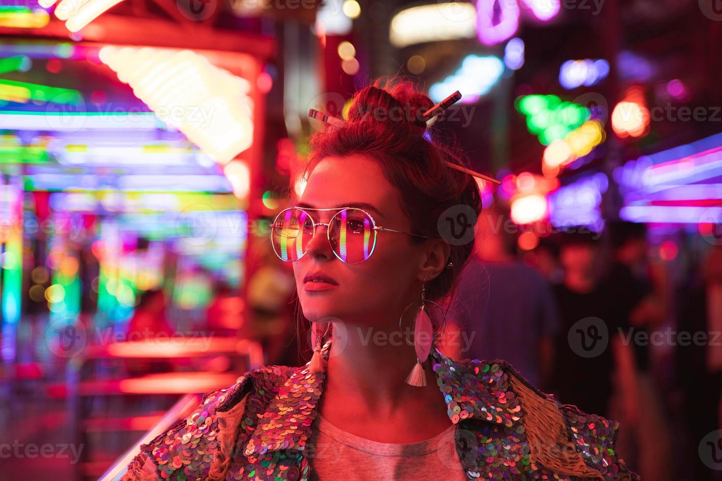 Stylish woman wearing jacket with shining sequins on the city street with neon lights photo