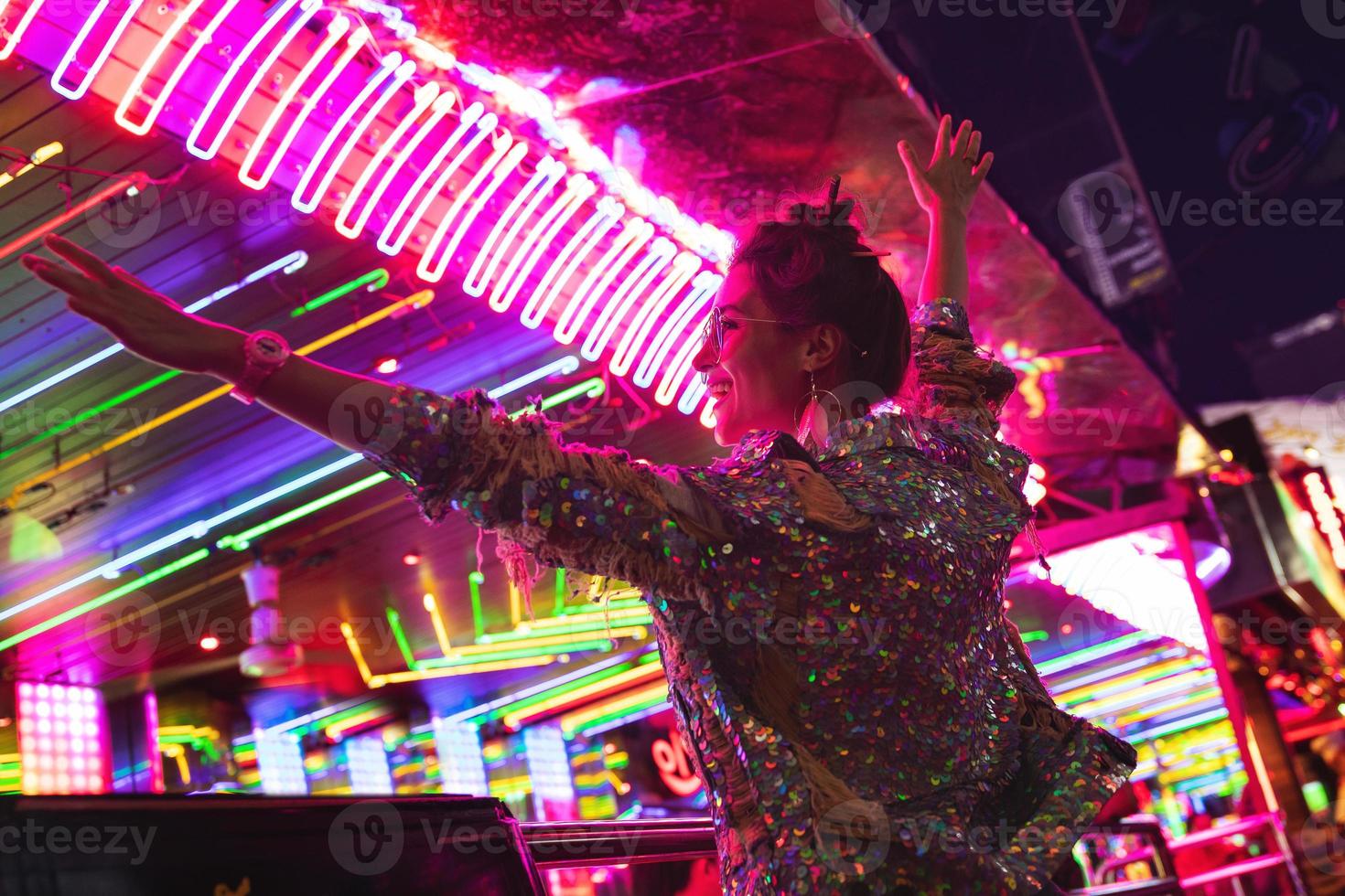 Stylish woman wearing jacket with shining sequins on the city street with neon lights photo