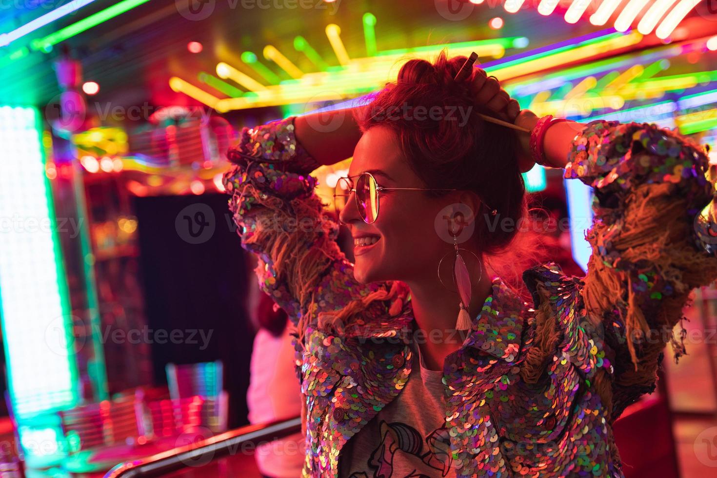 Stylish woman wearing jacket with shining sequins on the city street with neon lights photo