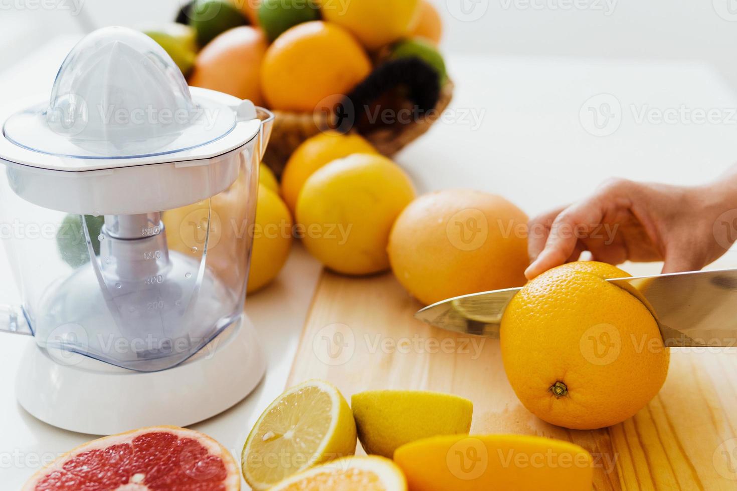 Female hands with knife cutting citrus fruits for homemade fresh juice photo