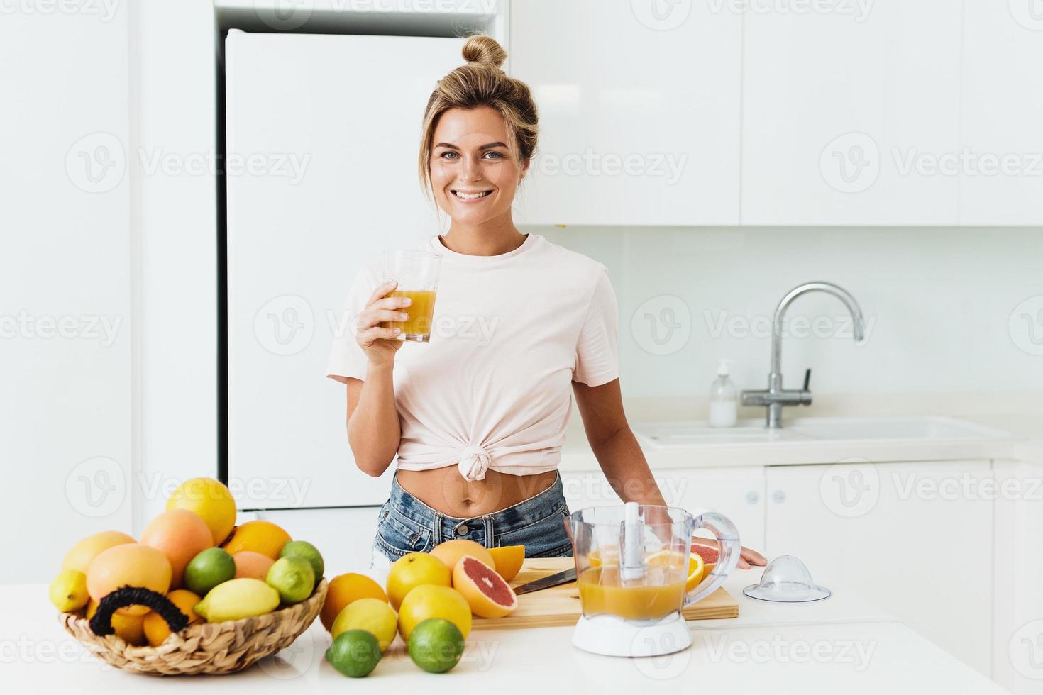 Cheerful woman with big glass of fresh orange juice at home photo