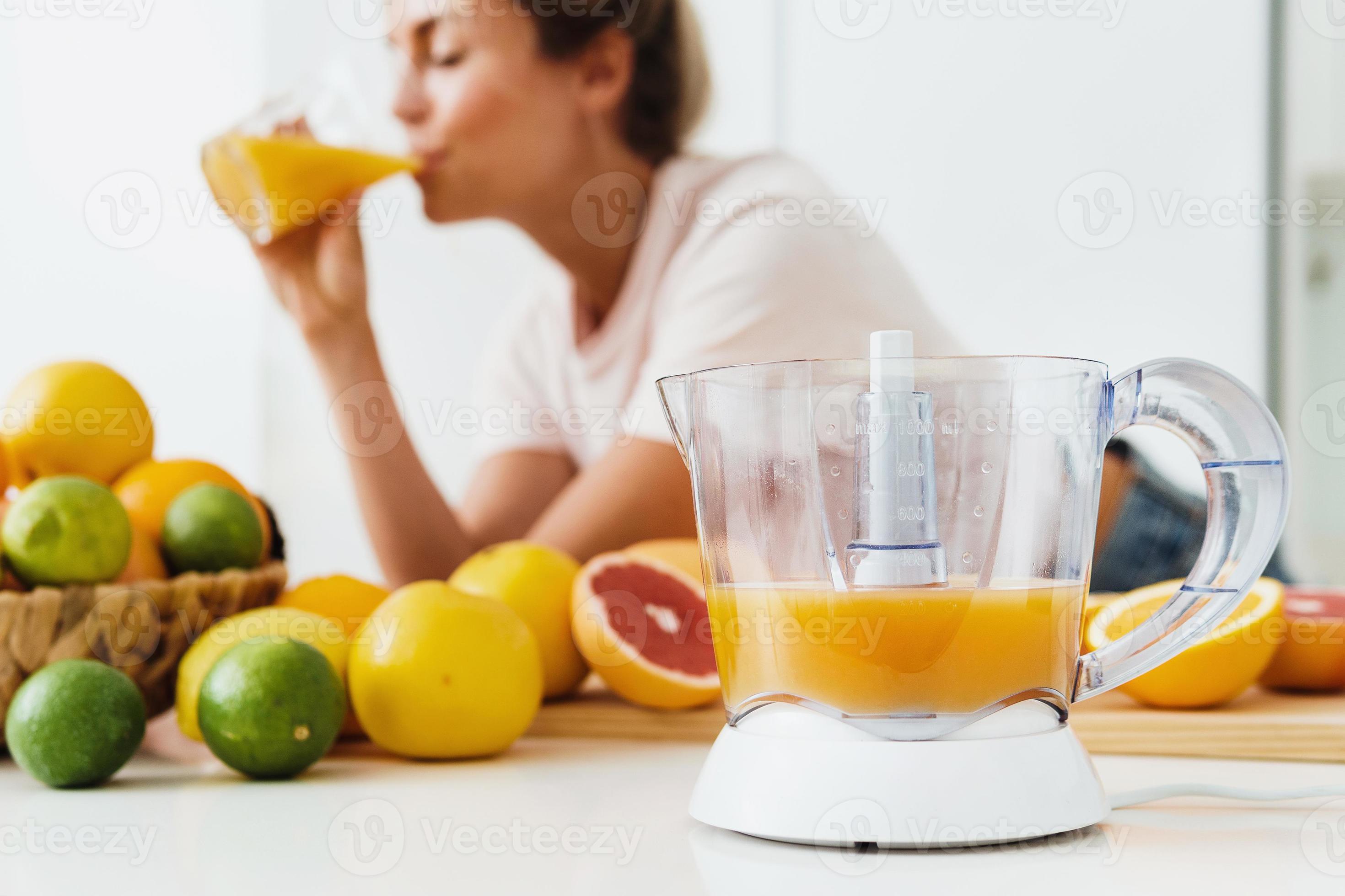 Citrus juicer and woman which drinking freshly squeezed homemade orange