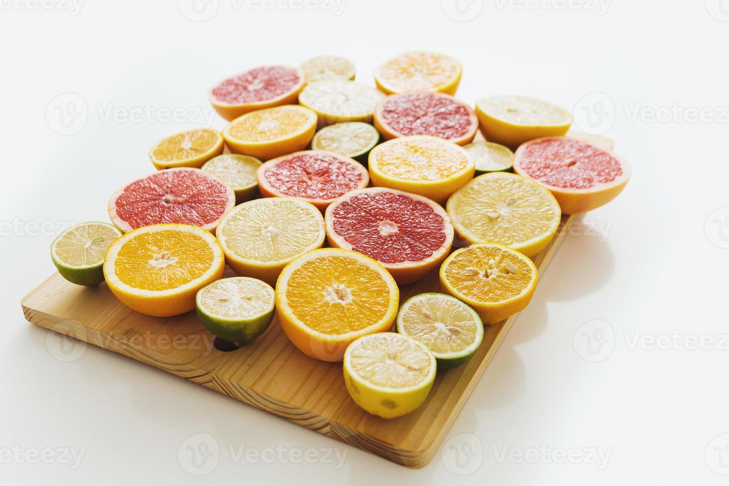 Sliced citrus fruits such as grapefruit, orange, lemon and lime on cutting board against white background photo