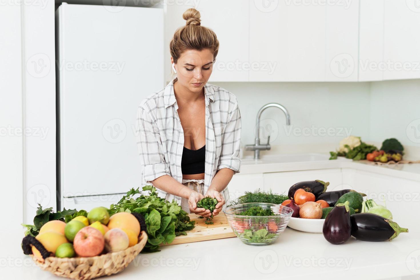 mujer bonita joven cocinando un plato vegetariano saludable en casa foto