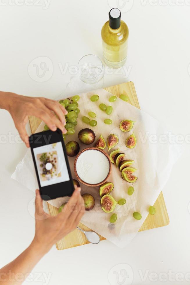 mujer tomando fotos de su delicioso yogur griego con higos junto a su smartphone