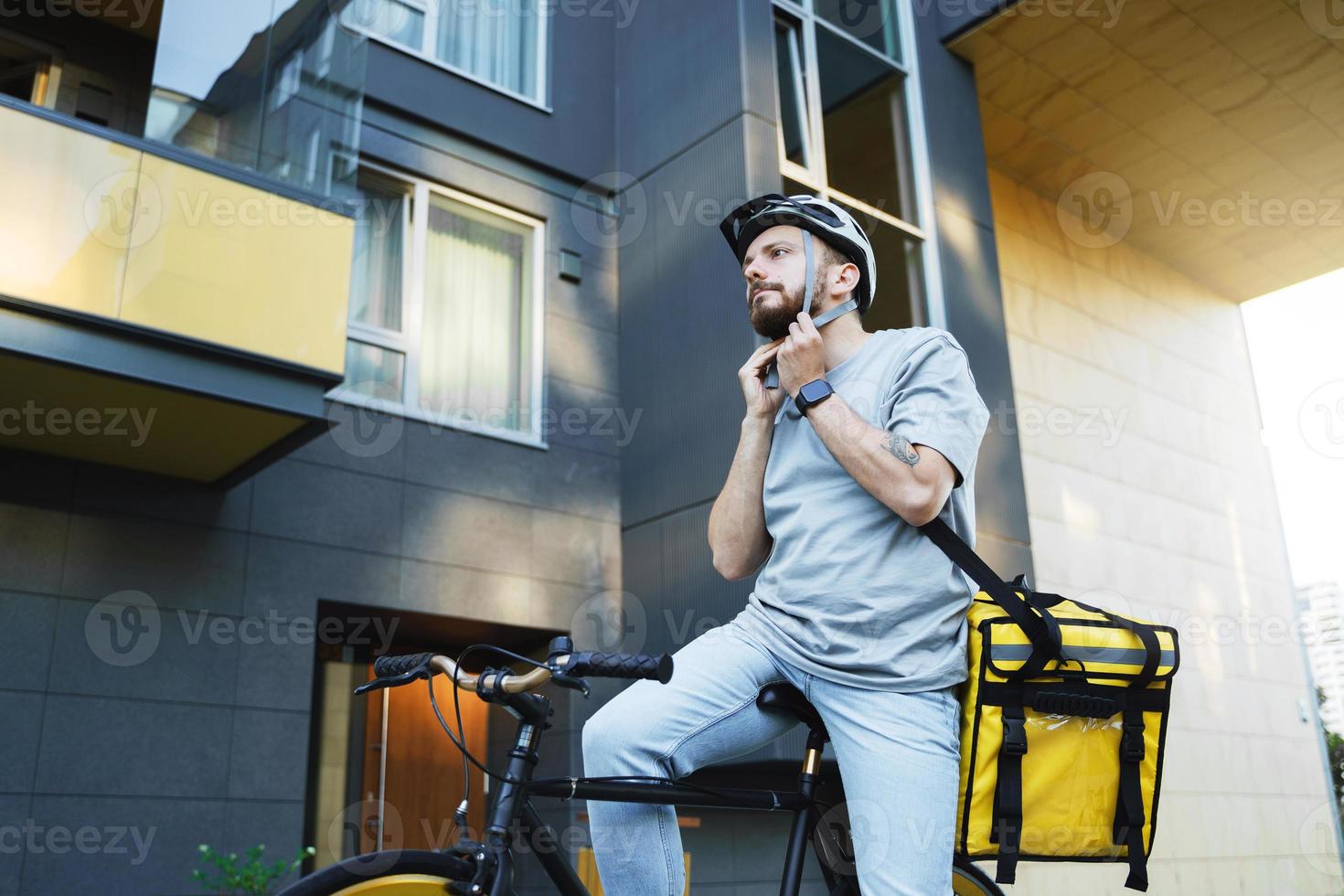 Express delivery courier on bicycle puts on helmet. photo