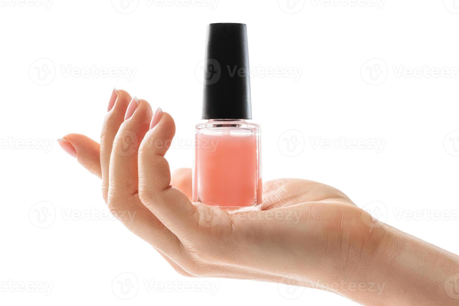 Female hand with beautiful french manicure holding bottle of pink nail polish against white background photo