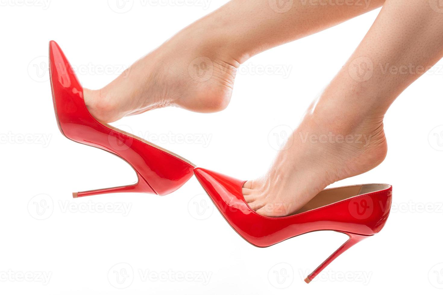 Female feet with red stiletto heels shoes on white background photo