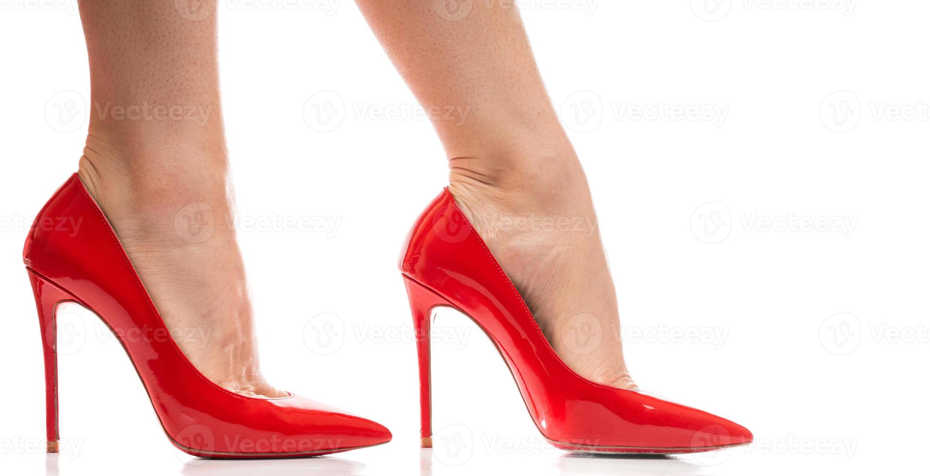 Female feet with red stiletto heels shoes on white background photo