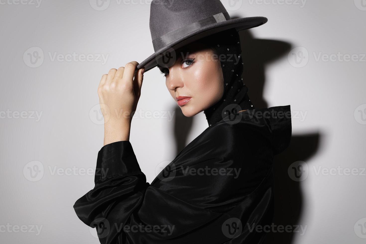 Portrait of young gorgeous woman wearing rhinestone-embellished balaclava and felted hat photo