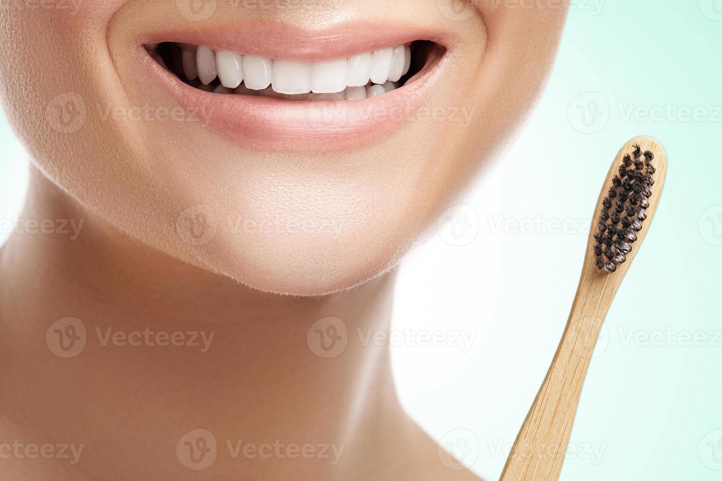 boca femenina con dientes blancos y cepillo de dientes de bambú foto