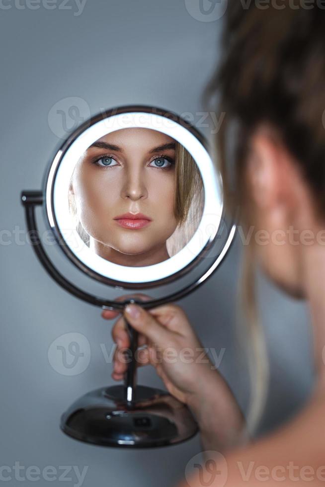Beautiful woman looking into the round mirror photo