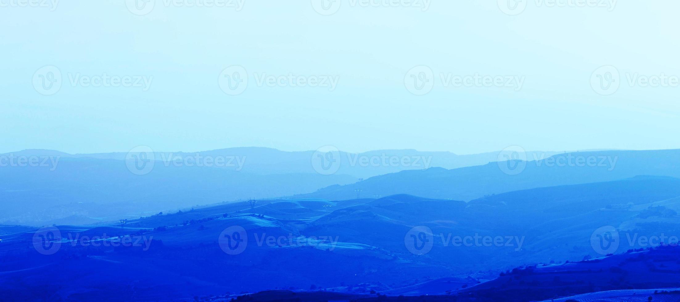 capas de cadenas montañosas apiladas en silueta azul. perspectiva aérea de colinas azules. foto