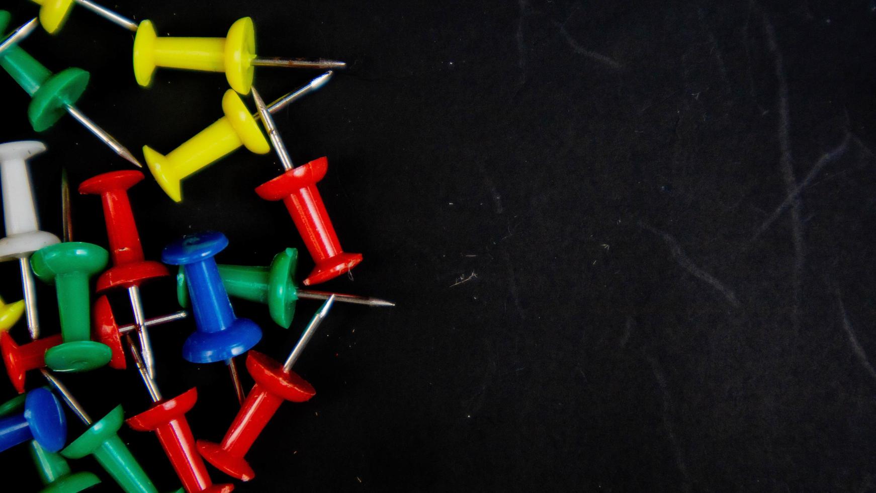 Chinchetas multicolores sobre un fondo negro foto