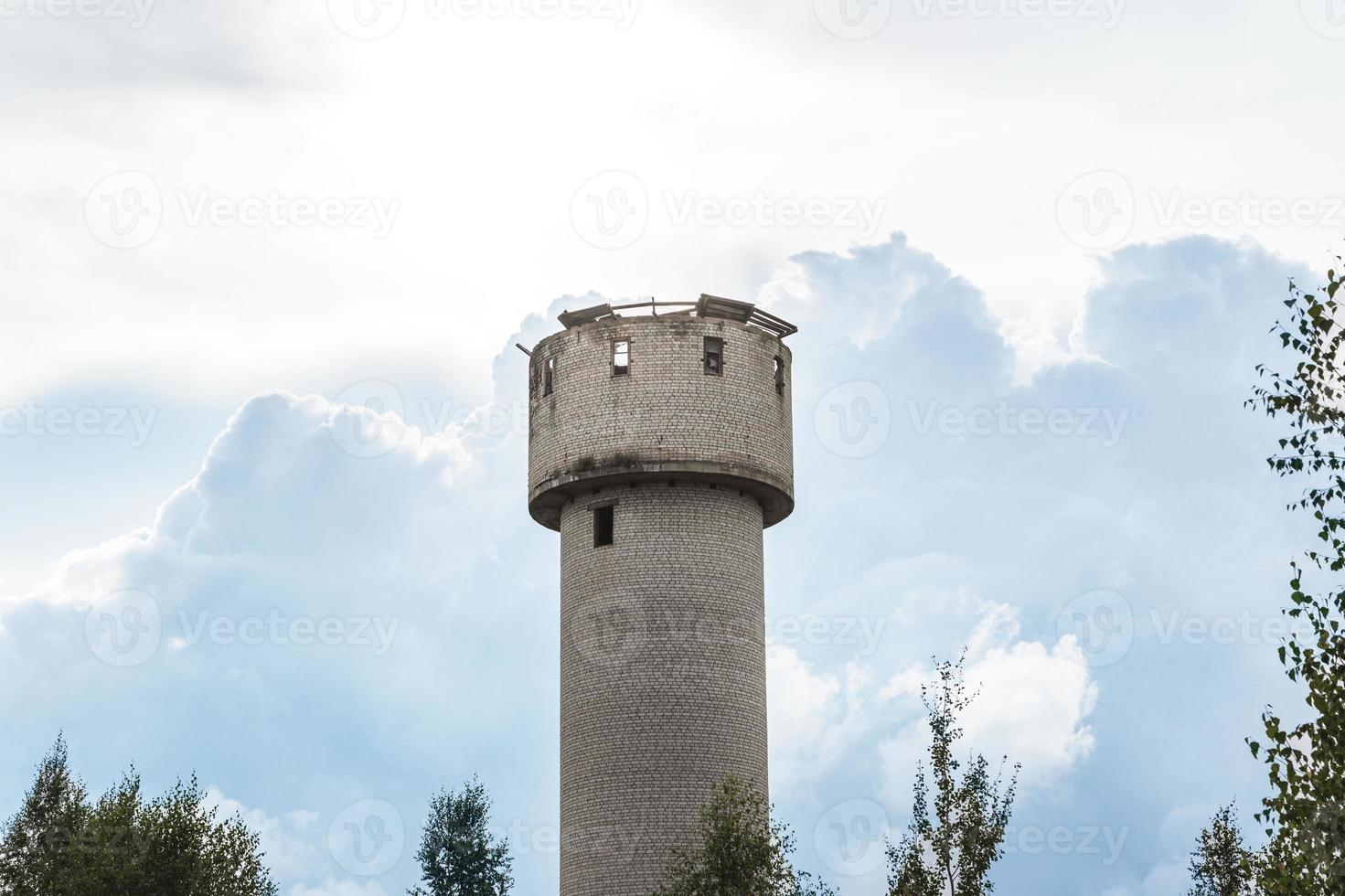 Exterior of abandoned water tower with collapsed roof and broken windows. photo