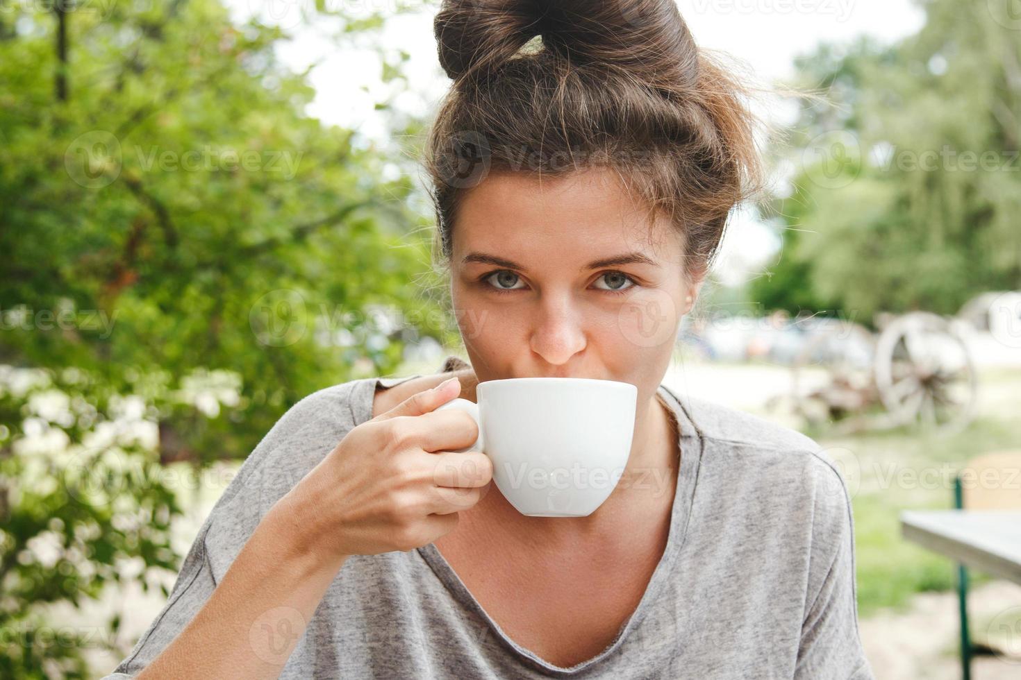 Young pretty woman drinking coffe in open air cafe. photo