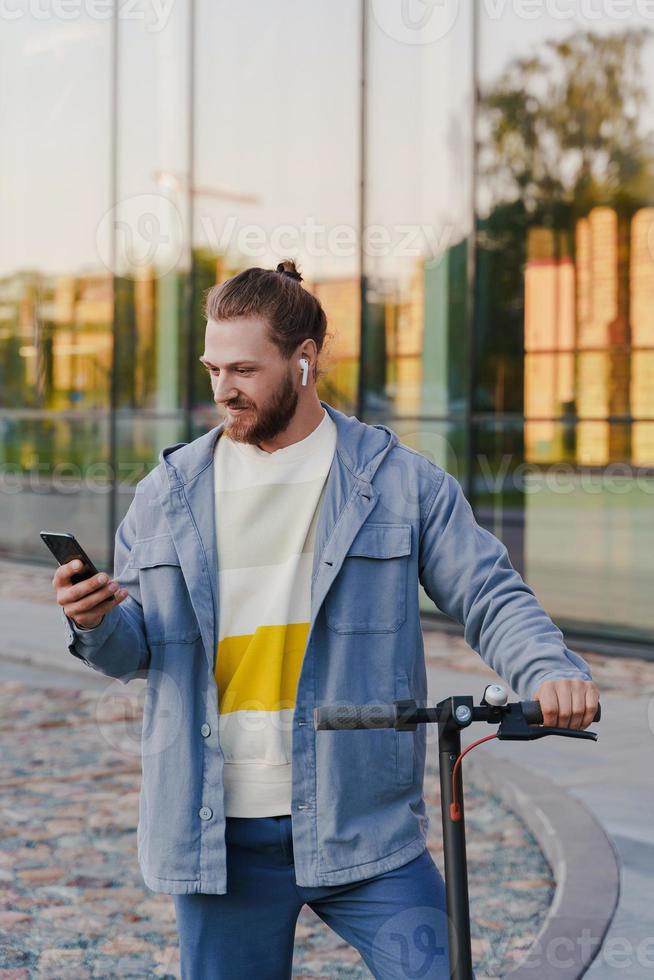 Man with e-scooter using  scooter-sharing system application on his smartphone photo