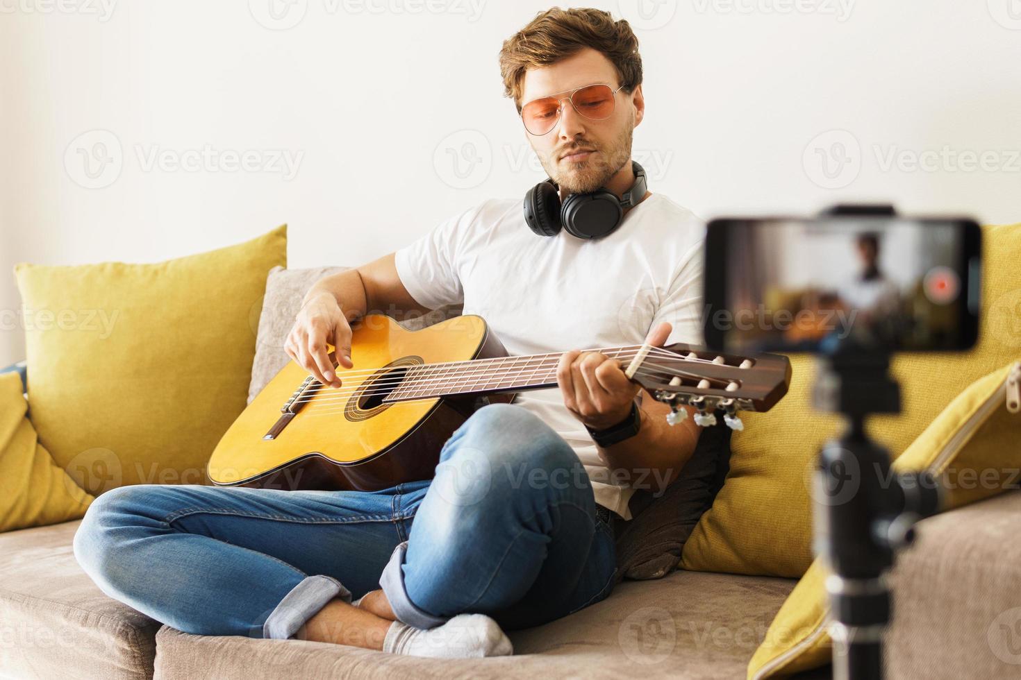 Musician blogger on sofa playing acoustic guitar photo