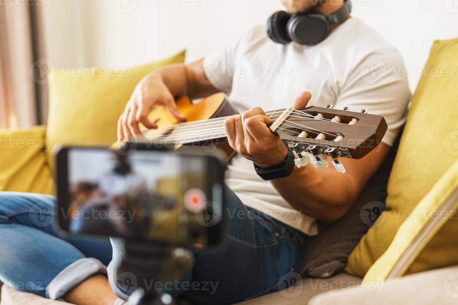 blogger músico en el sofá tocando la guitarra acústica foto