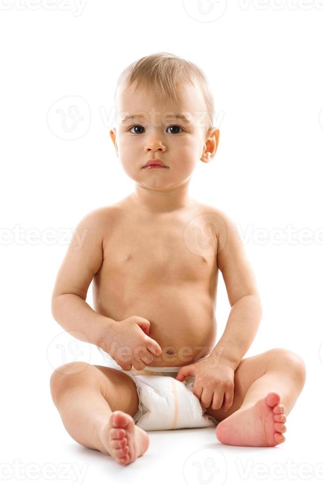Curious healthy little boy in diaper sitting and looking. photo