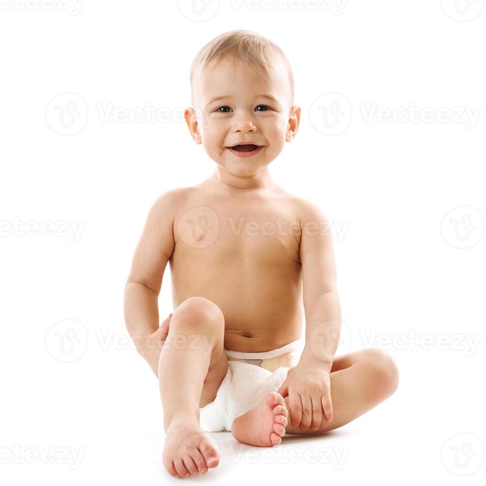 curioso niño sano en pañales sentado y riéndose. foto