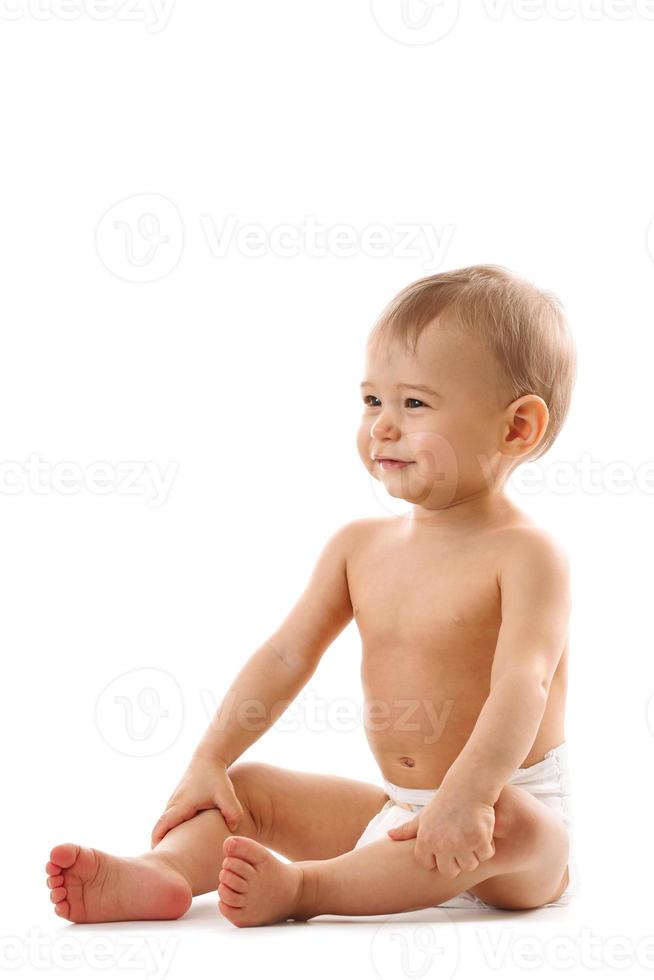 Curious healthy little boy in diaper sitting and smiling. photo